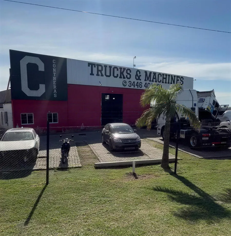 Galpón de Trucks & Machines sobre la Ruta 14: cartel en el techo y paredes rojas, con camiones en el predio